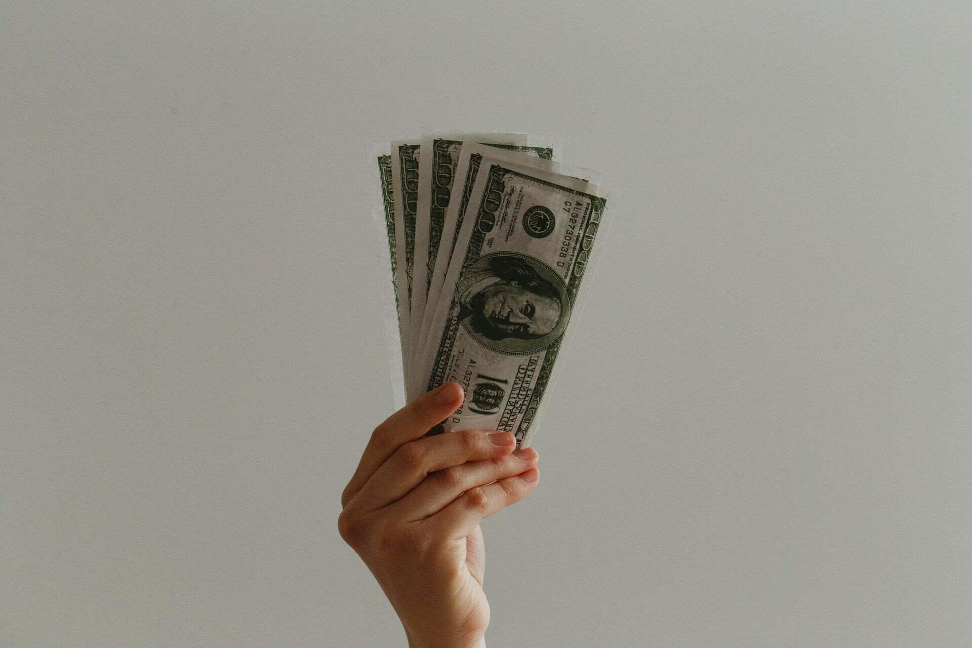 a hand holding a fanned out dollar bills