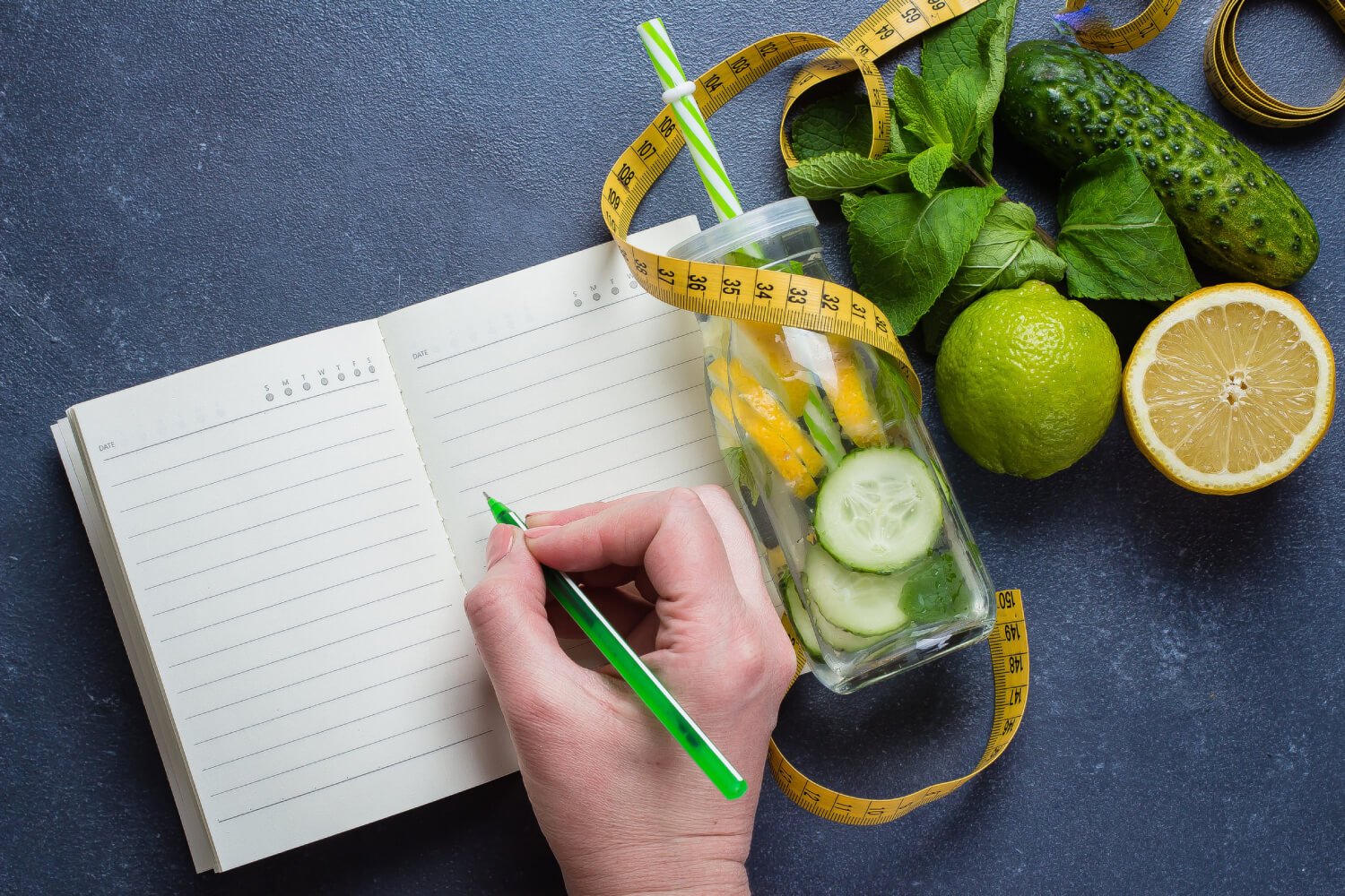 a hand holding a green marker and a lemon on a black surface